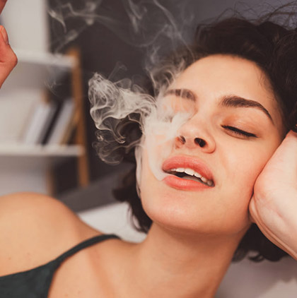 Woman relaxing indoors while exhaling smoke